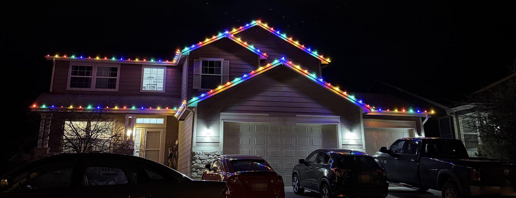 Multicolor C9 Christmas lights outlining the rooflines and peaks of a two-story home
